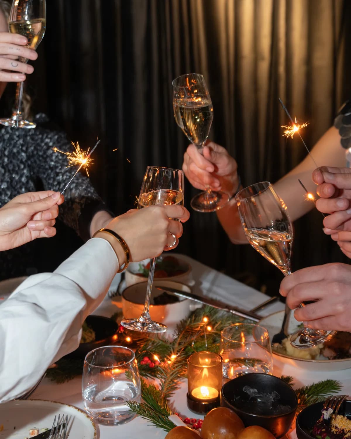 Guests raising champagne glasses over a candlelit table